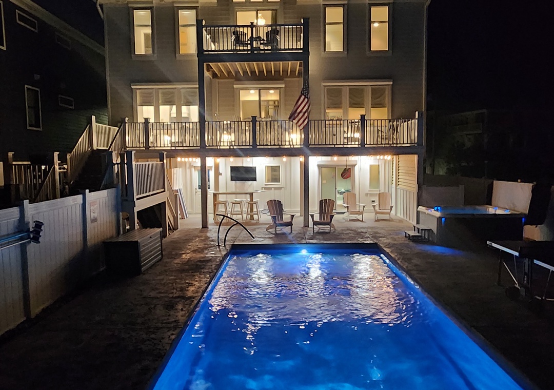 The illuminated property and sparkling pool create a stunning nighttime scene, showcasing the vacation rental's welcoming exterior and inviting outdoor amenities for evening relaxation.