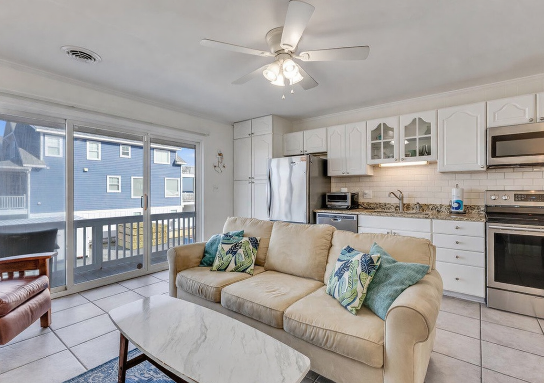 Your bright open-concept space blends comfort with convenience, featuring a fully-equipped kitchen and cozy living area with ocean-themed accents.