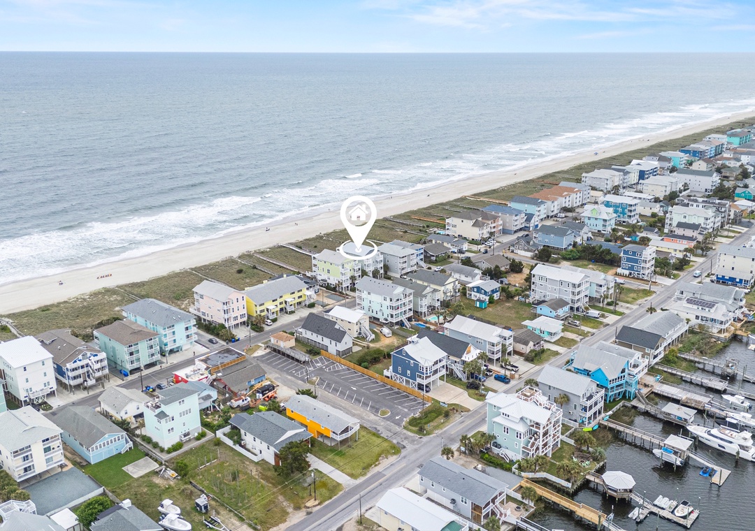 Aerial view of a coastal beachside community with beach access, waterfront homes, and marina facilities, situated between ocean and inland waterway.
