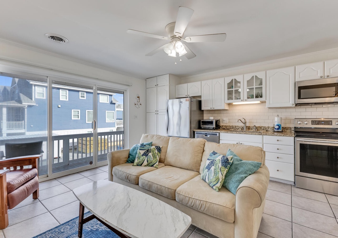 Your bright open-concept space blends comfort with convenience, featuring a fully-equipped kitchen and cozy living area with ocean-themed accents.