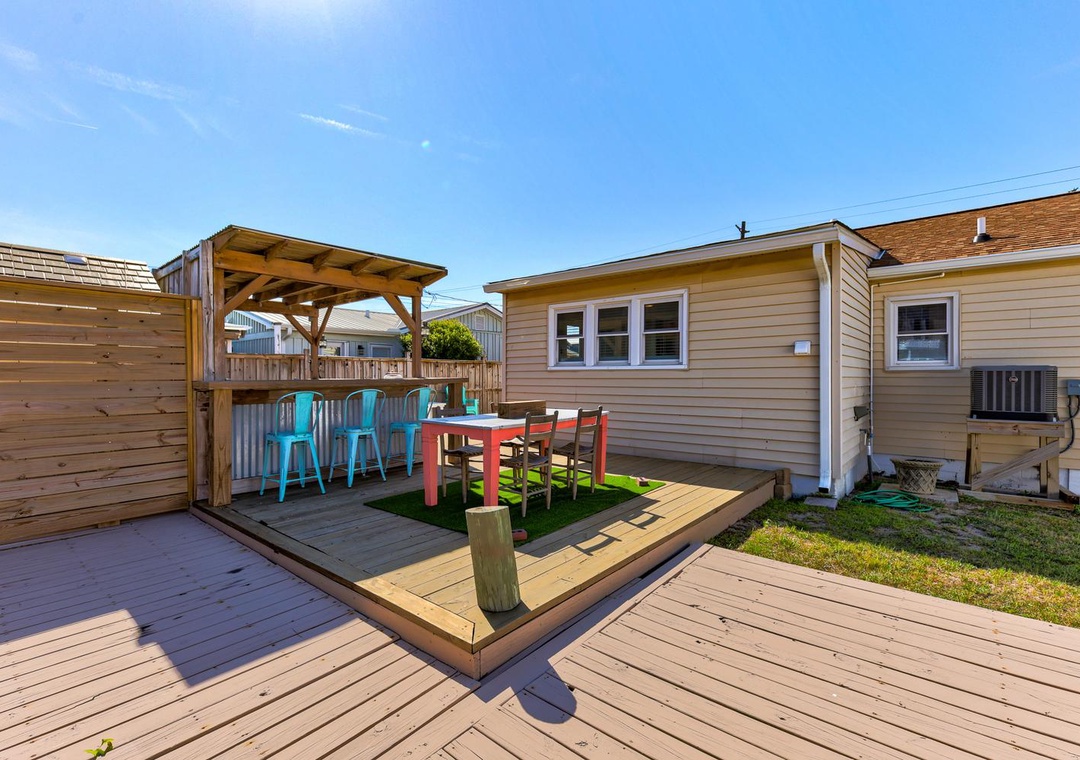 Step onto your private deck where bright turquoise stools await at the outdoor bar, perfect for morning coffee or evening cocktails under the pergola.