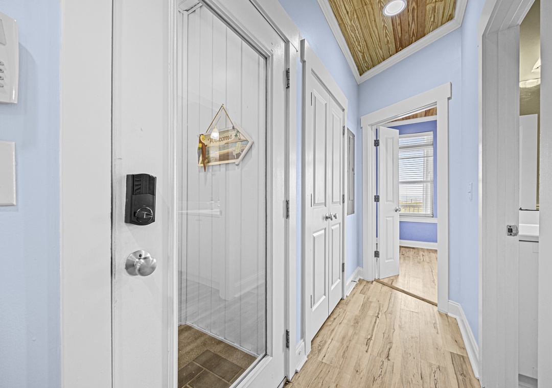 Step into your coastal retreat through this charming hallway, where natural light pours in from a skylight above and rooms await your arrival.