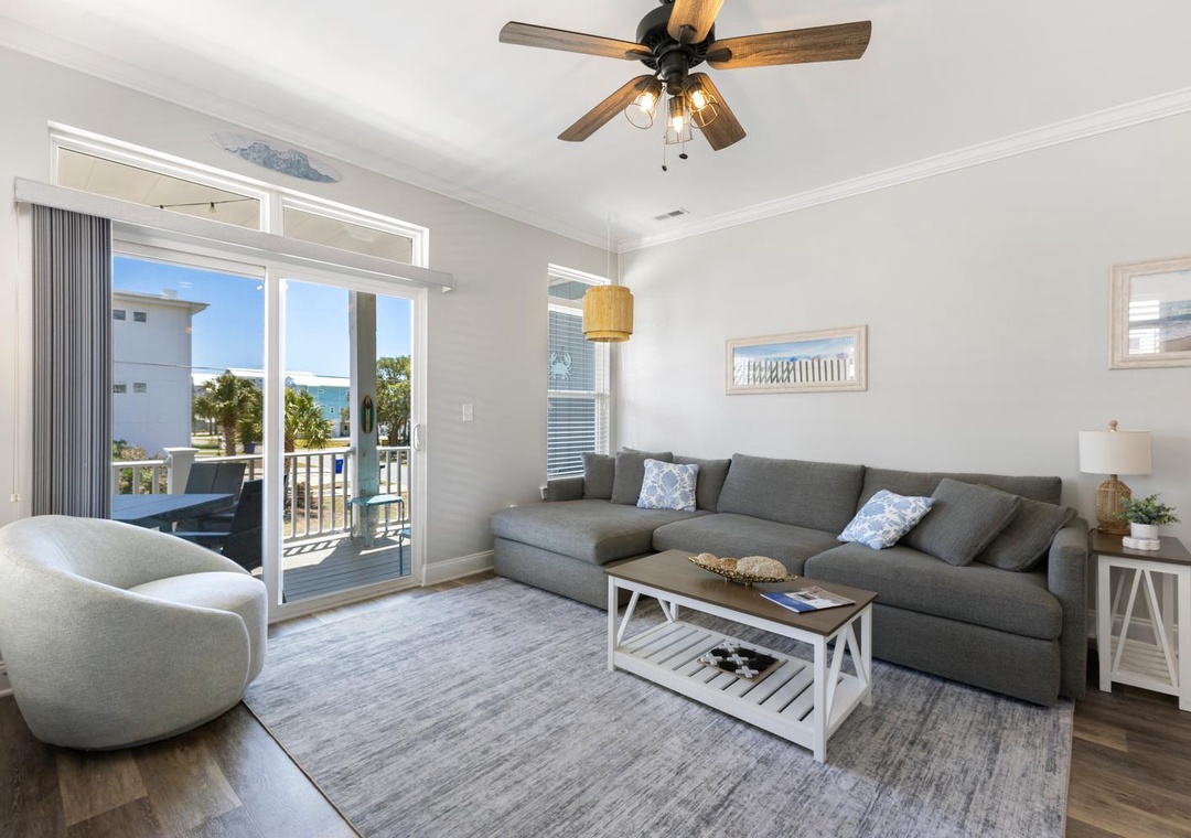 Unwind in your bright coastal retreat with a plush sectional and warm wood accents, where sunlight streams through glass doors opening to your private balcony with ocean views.