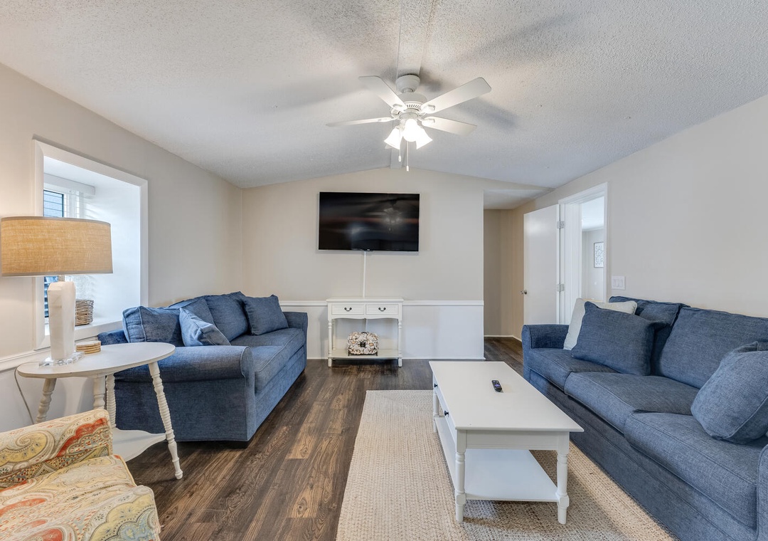 Your living room sanctuary features plush navy sofas and a ceiling fan for perfect relaxation after your adventures.