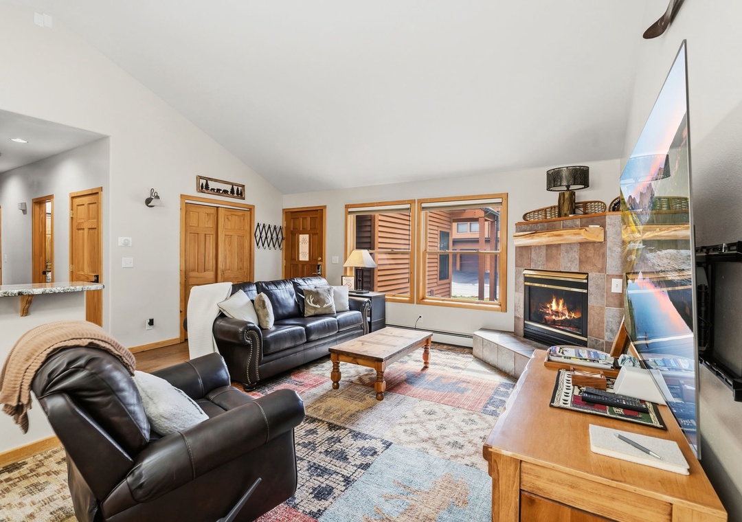 Unwind in your spacious living room with plush leather seating, a cozy fireplace, and large windows filling the space with natural light.