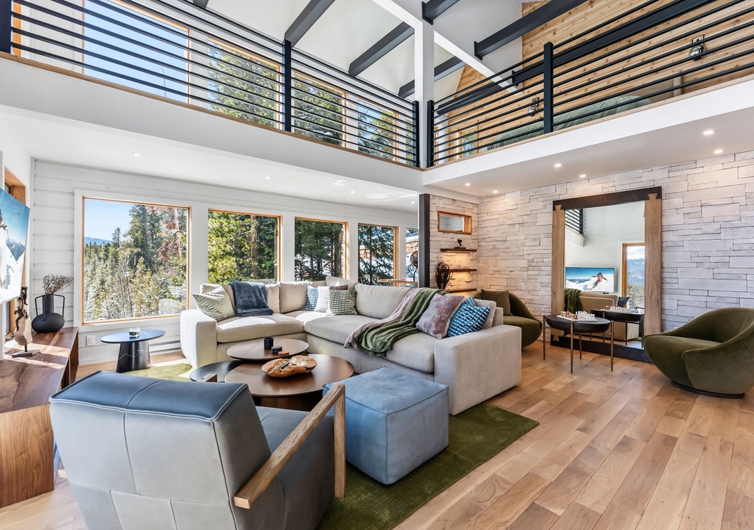 Relax in your spacious living area with soaring ceilings, modern furnishings, and forest views through floor-to-ceiling windows.