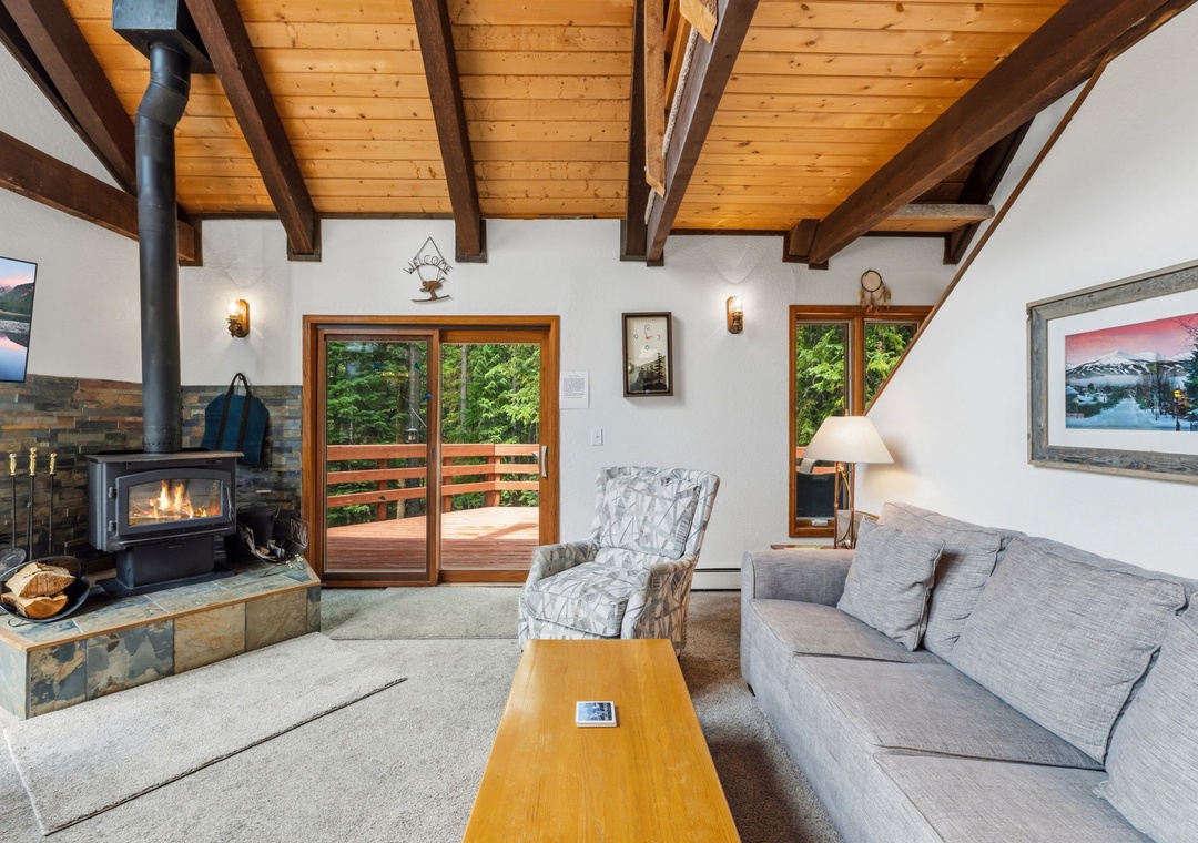 Curl up in this inviting living room with soaring wood-beam ceilings, a cozy fireplace, and French doors opening to your private deck surrounded by greenery.