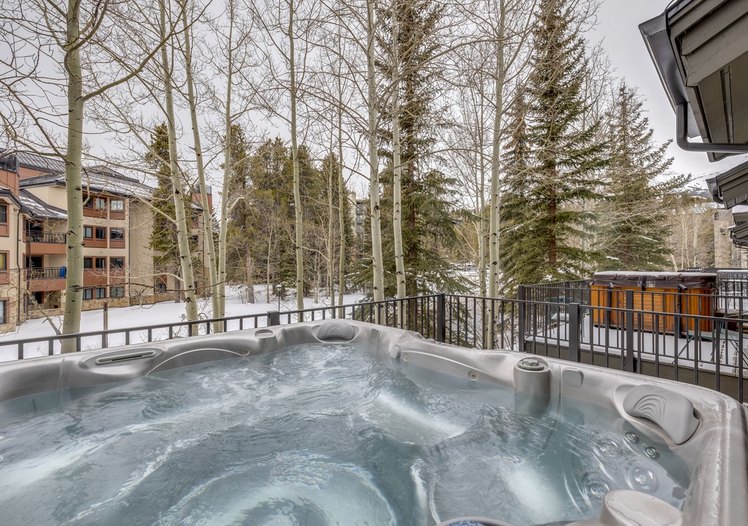Sink into bubbling warmth while snow-dusted trees frame your private hot tub retreat on this peaceful balcony.