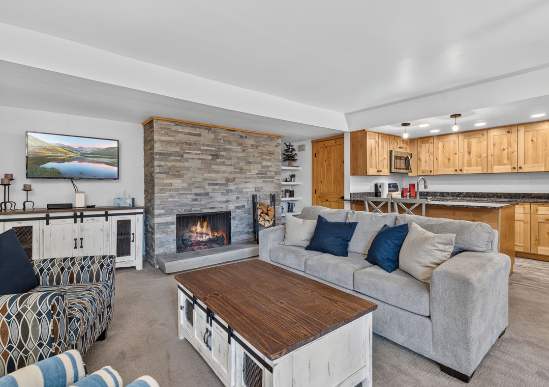 Unwind in your open-concept living area featuring a cozy fireplace, plush seating, and a fully-equipped kitchen. Perfect for mountain retreats, your group will love gathering here after a day of adventure.
