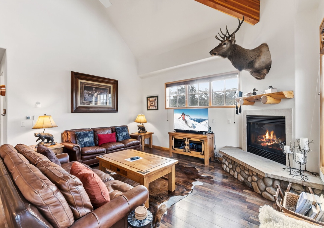Cozy up by the crackling fireplace in your mountain lodge retreat, featuring plush leather seating and rustic charm perfect for après-ski relaxation.