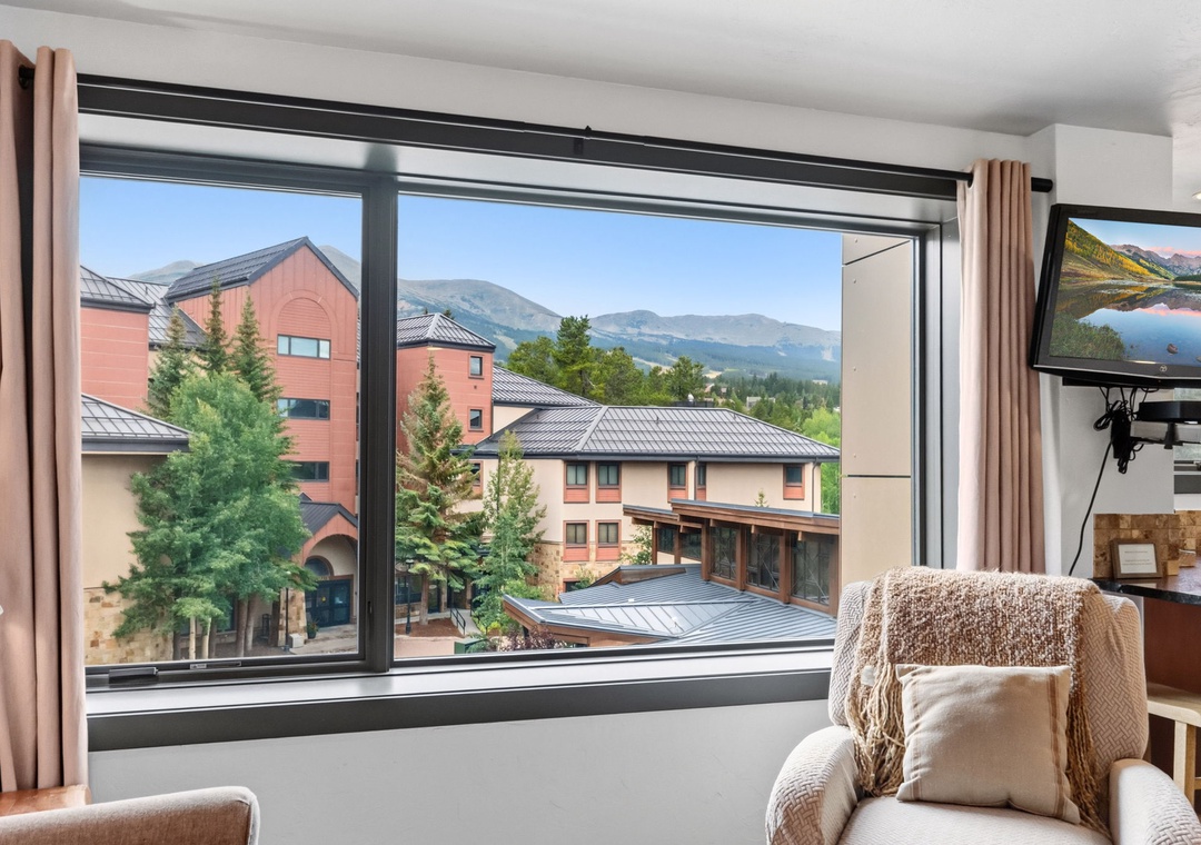 Sink into your cozy armchair and let your gaze drift across the majestic mountain skyline framed by sweeping windows—your perfect retreat for morning coffee or evening relaxation.