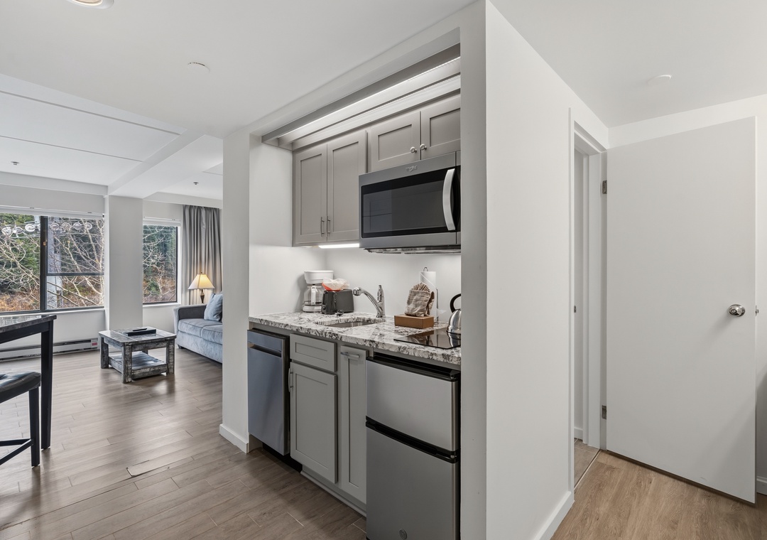 Your fully equipped kitchenette features modern appliances and granite countertops, perfect for preparing meals at home. The open floor plan flows seamlessly into the bright living space.