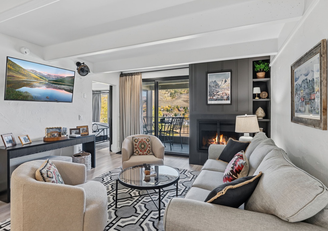 Gather in this beautifully designed living space, where plush seating frames the warm fireplace and mountain light streams through glass doors to your private balcony.