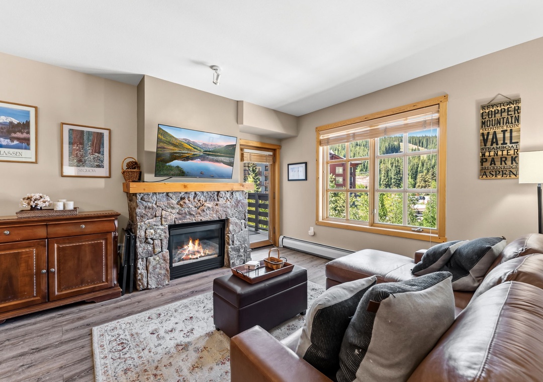 Settle into your cozy living room with a crackling stone fireplace and sweeping mountain views through large windows—your perfect retreat after a day of adventure.