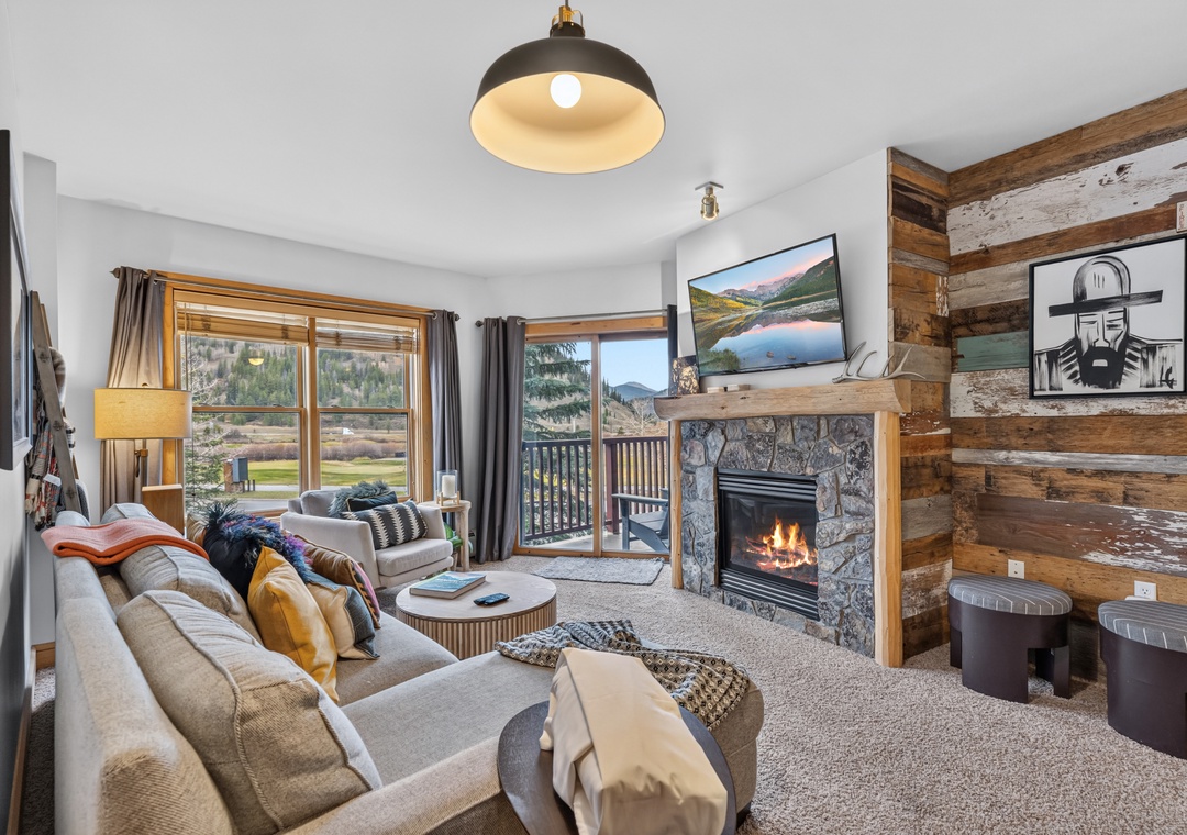 Sink into plush seating by your own stone fireplace, where rustic wood accents and mountain light through the glass doors create your perfect retreat.