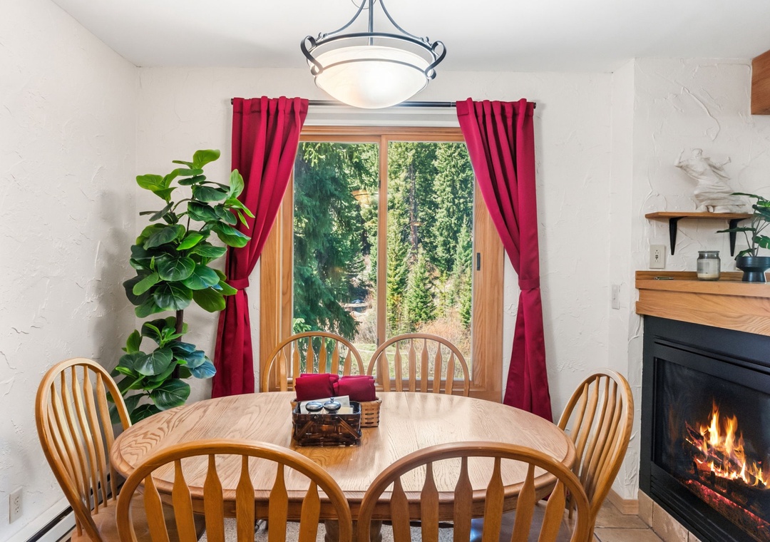 Gather around this inviting dining table where warm firelight and forest views create the perfect backdrop for your meals and memorable conversations together.