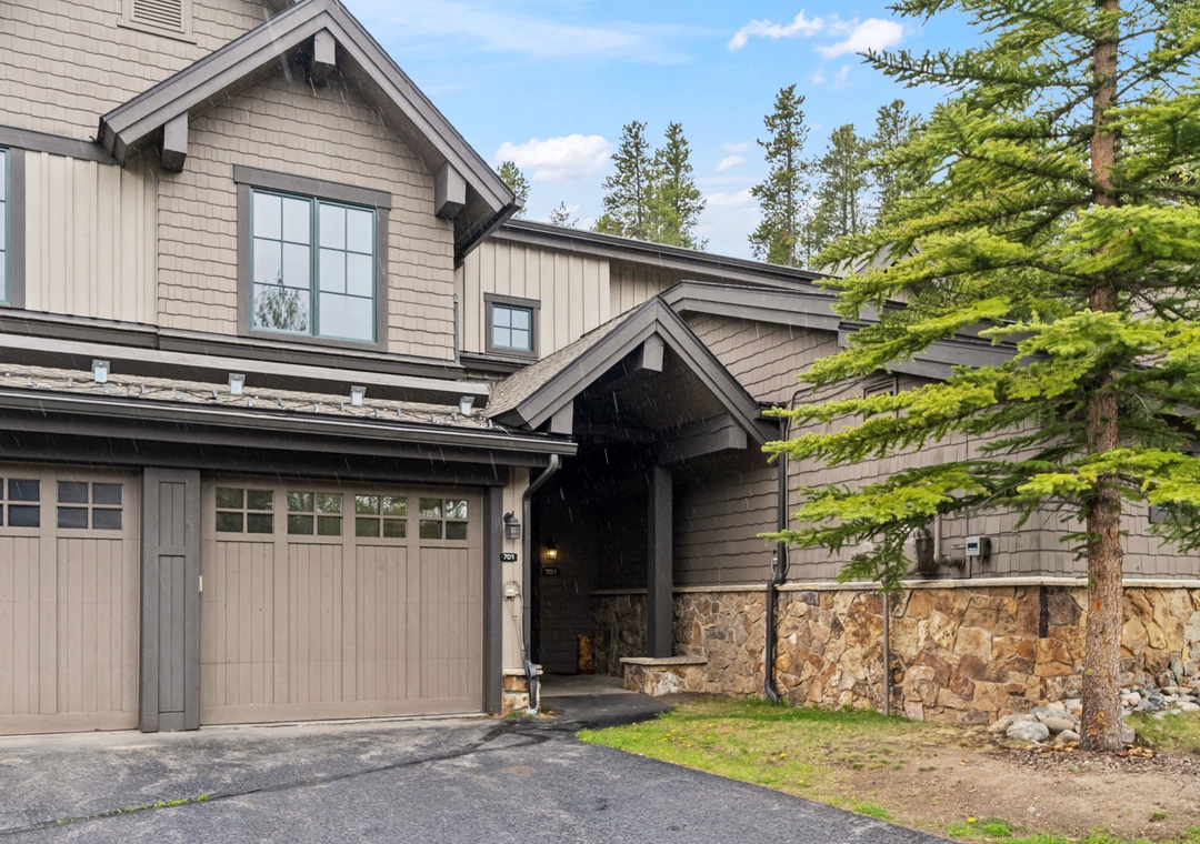 Mountain retreat with stone accents and natural surroundings, offering a private driveway and covered entrance framed by towering pines.