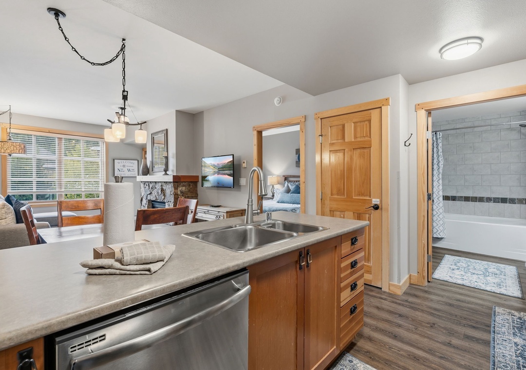 Your inviting kitchen island connects seamlessly to cozy living and dining spaces, with warm wood tones and natural light creating the perfect home-away-from-home gathering spot.
