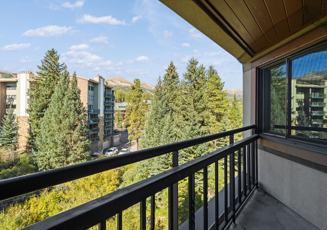 A private balcony offering panoramic mountain views framed by lush trees and open sky. Your perfect spot for morning coffee or evening relaxation amid fresh alpine air.