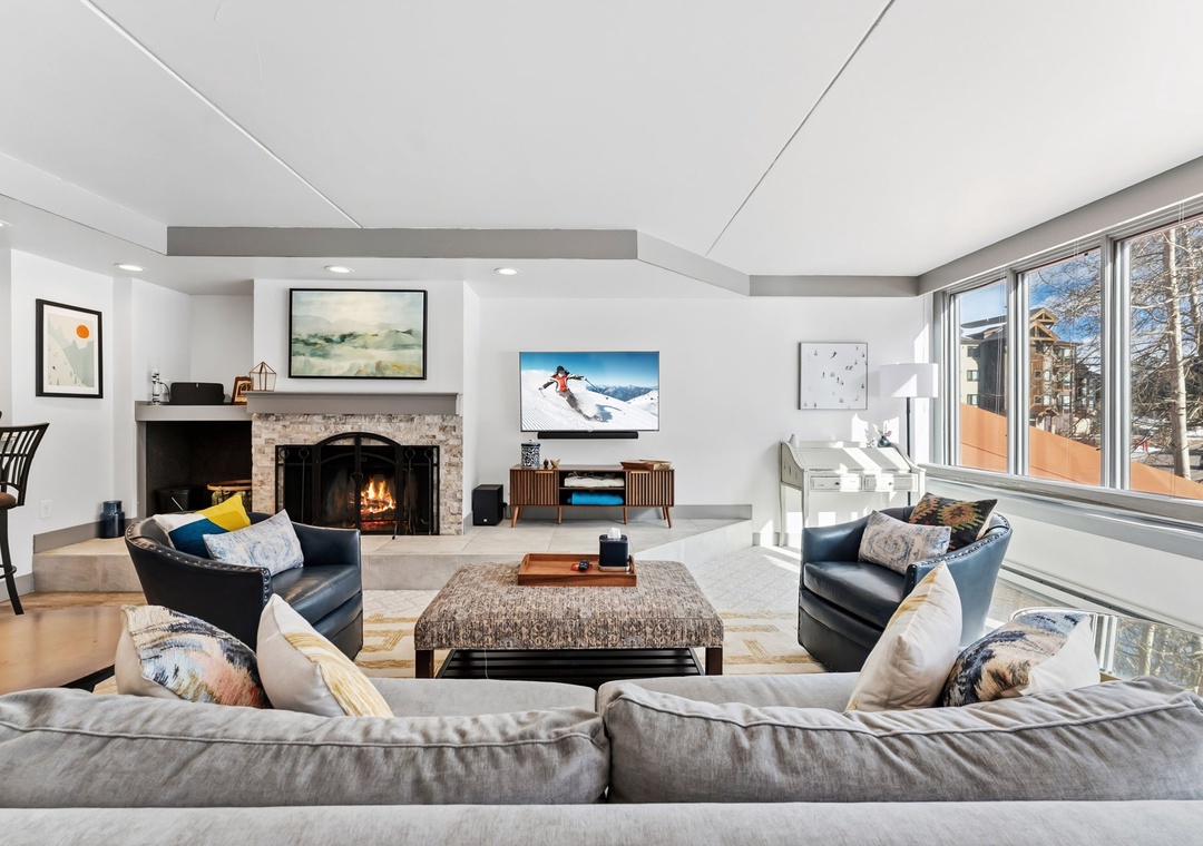 Sink into plush seating by your crackling fireplace, where panoramic windows frame stunning views and modern comfort meets mountain elegance.