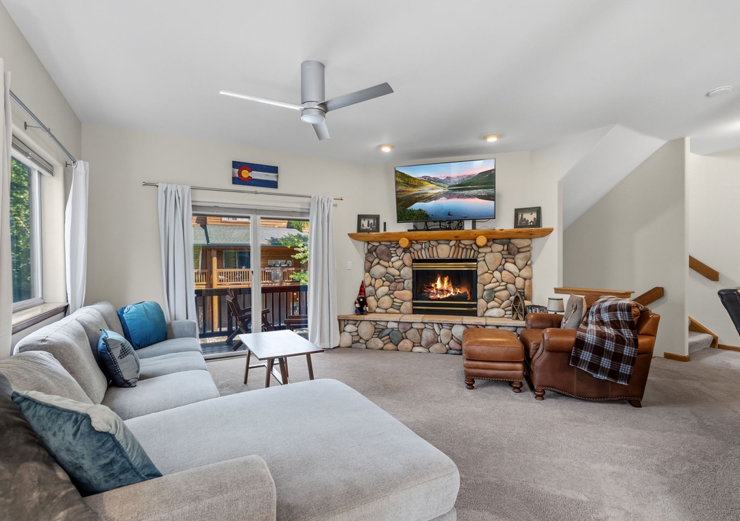 Unwind in your spacious living room where a stone fireplace sets a cozy mood beneath vaulted ceilings. Sink into plush seating, enjoy natural light streaming through the balcony doors, and feel instantly at home.