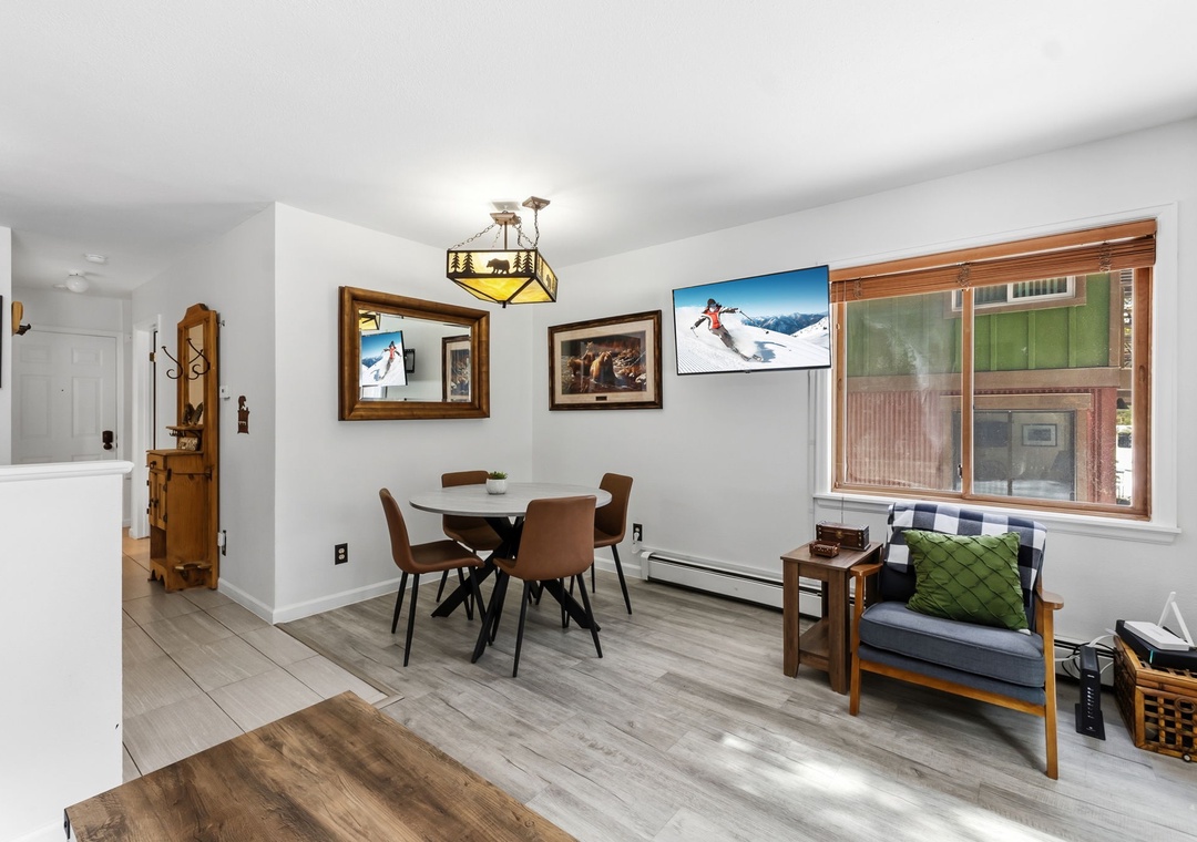 Your bright living space blends modern comfort with mountain style, featuring a cozy dining area and relaxing seating by sunny windows.