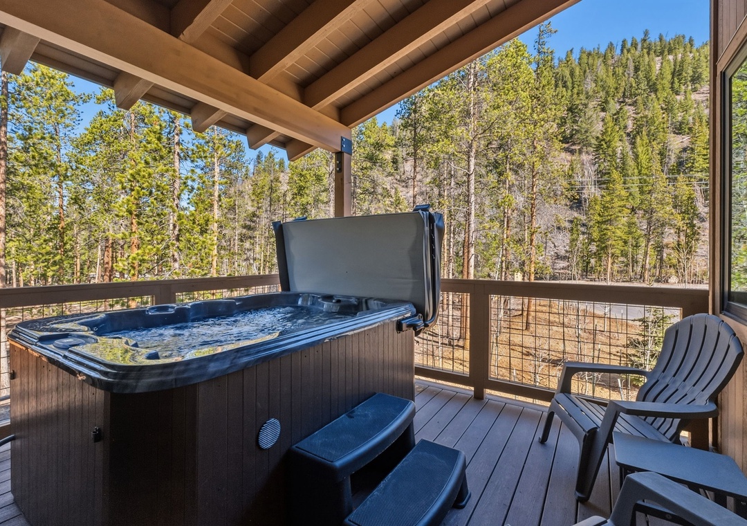 Your private deck with private hot tub and sitting area that overlooks snow-dusted forest