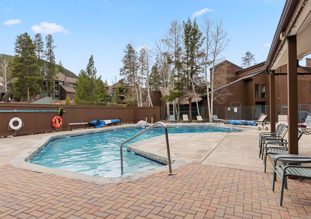 The complex outdoor pool area features a heated pool surrounded by lounge chairs and mountain views—plus hot tubs located just inside!
