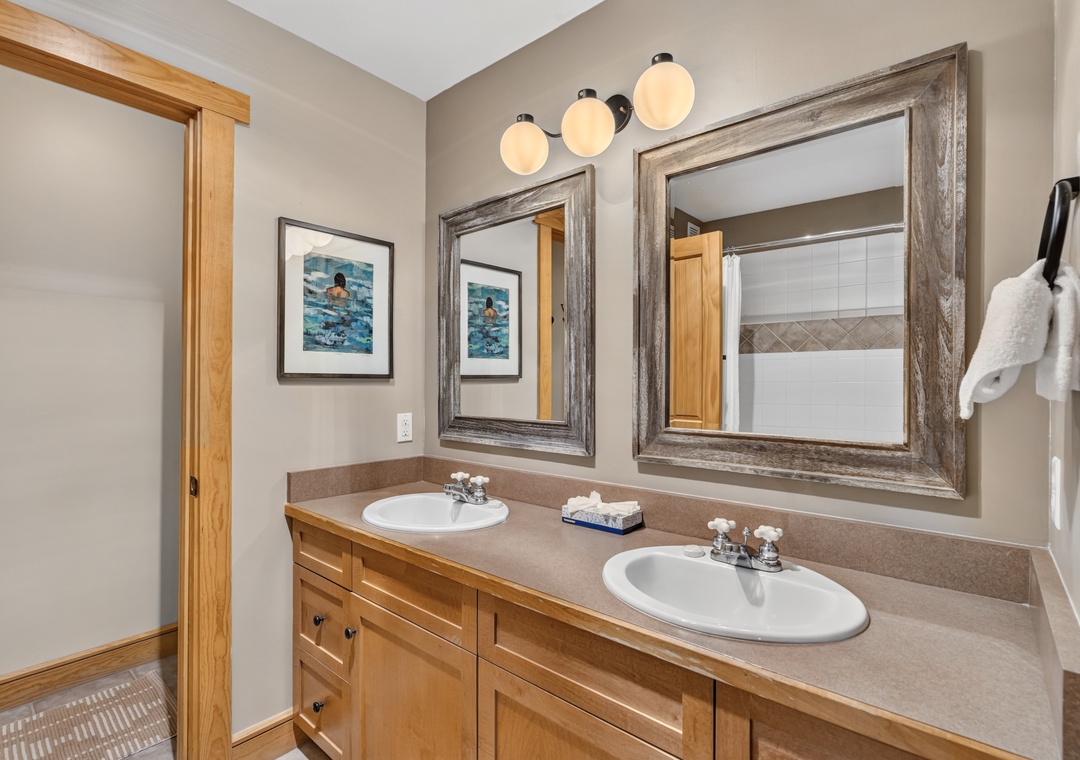 Freshen up in your spacious bathroom with dual sinks, warm wood vanity, and rustic framed mirrors—perfect for getting ready together before your next adventure.
