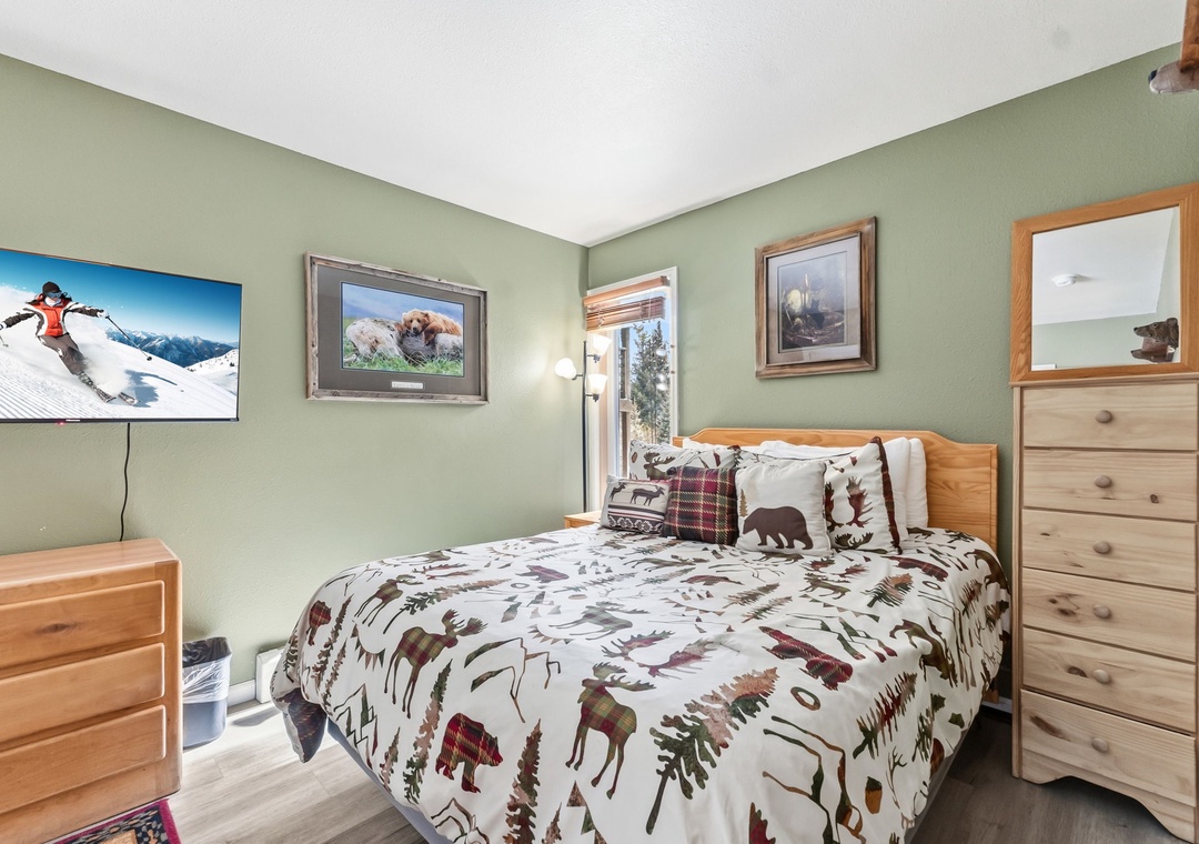 Cozy bedroom with mountain-themed decor and TV for your perfect retreat after outdoor adventures.