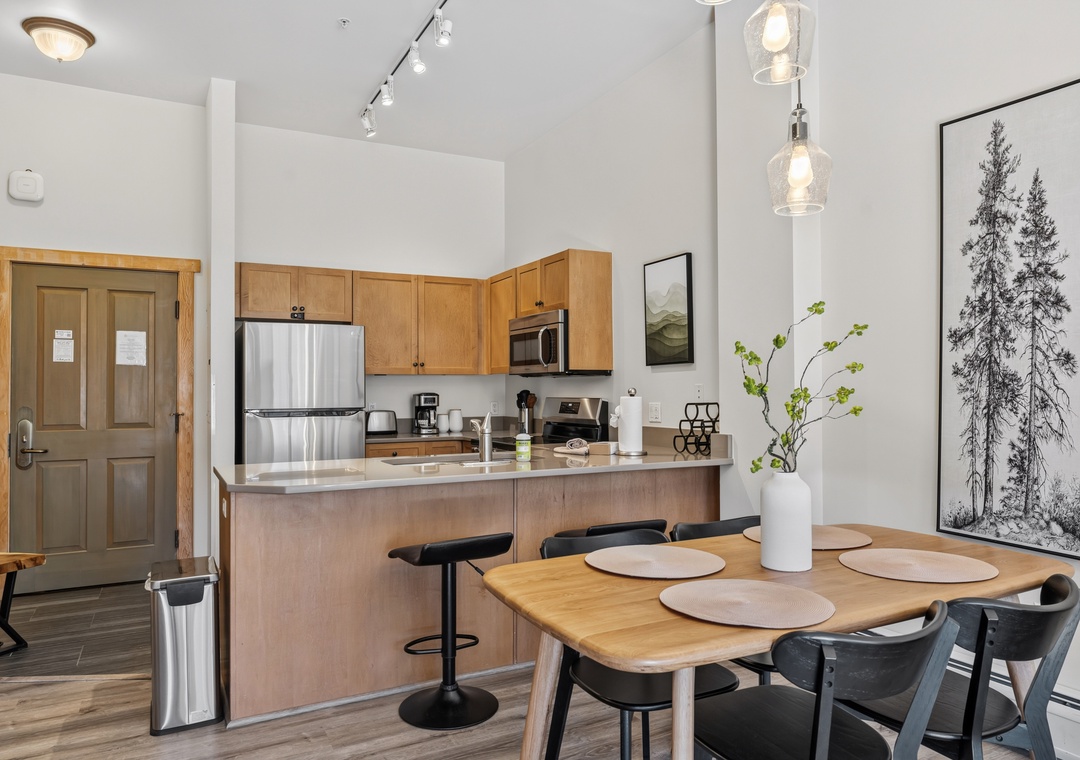 Step into your open-concept kitchen and dining space, where light wood cabinetry meets modern stainless steel appliances. Gather around the dining table beneath elegant pendant lighting, ready for memorable meals and conversations.