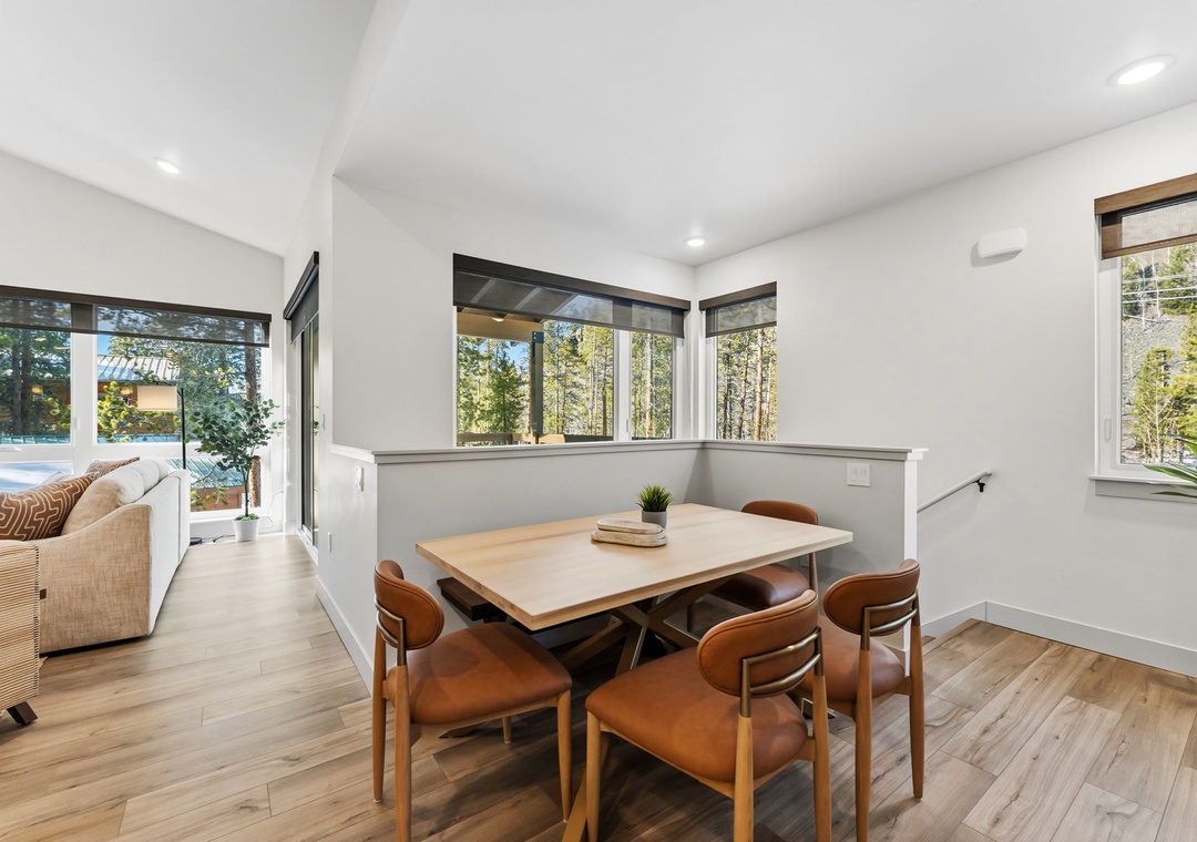 Gather around your bright dining table surrounded by windows that frame peaceful forest views, creating the perfect spot for memorable meals.