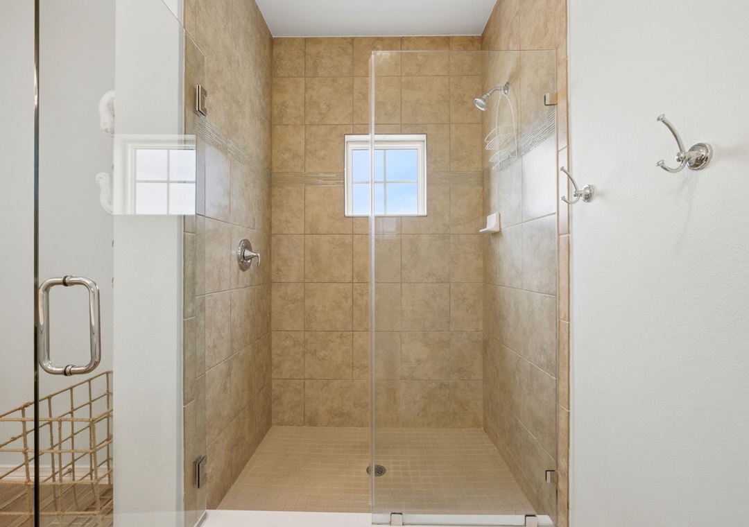 A spacious walk-in shower with neutral tiles and dual rainfall showerheads invites you to unwind after a day of adventure.