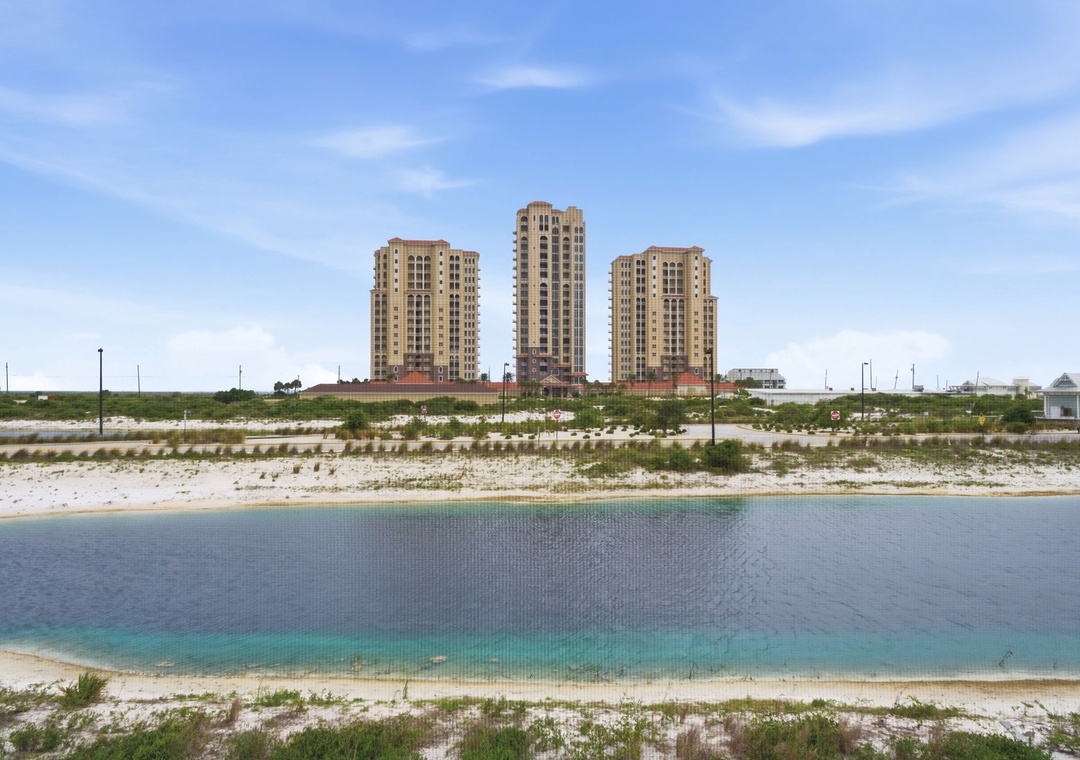 Beachfront property towers rise above pristine white sand and crystal-clear turquoise waters, offering a peaceful coastal setting for your vacation retreat.