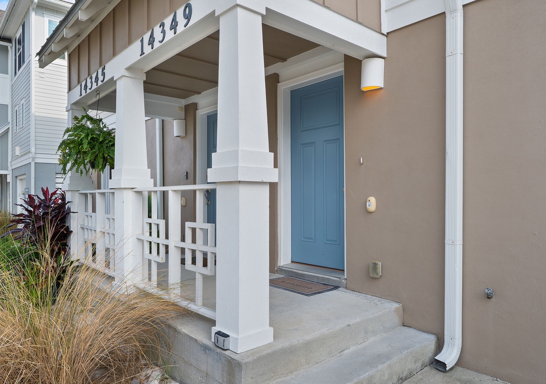 Saltwater & Sunsets- A welcoming front entrance with a cheerful blue door and modern architectural details marks the start of your coastal getaway.