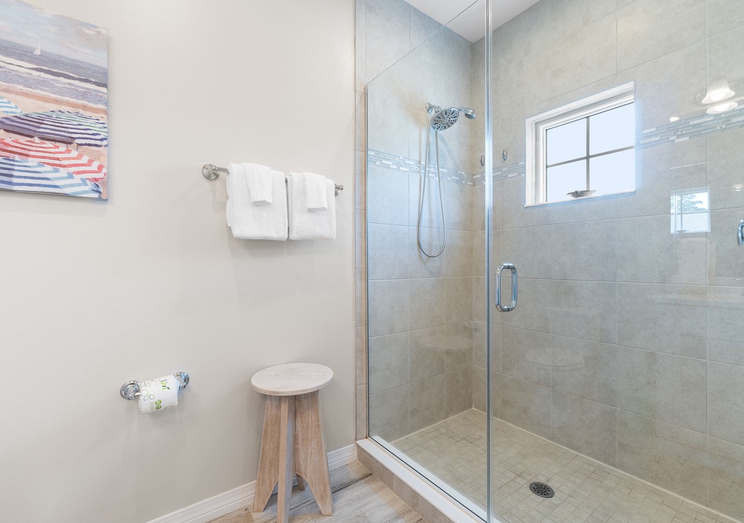 Turtles Nest- Step into your spa-like bathroom, where a spacious walk-in shower with sleek glass doors awaits. Natural light pours through the window, and fresh towels are thoughtfully laid out for you.