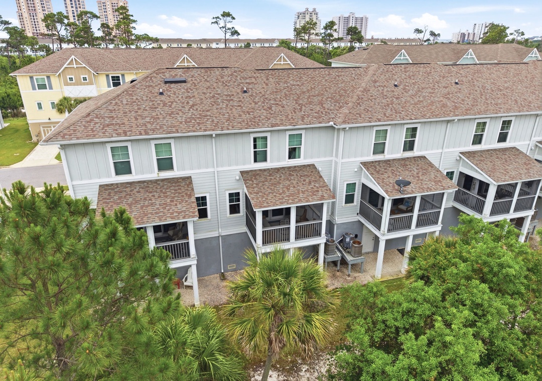 Turtles Nest- Aerial view of the property's multi-unit coastal townhomes, surrounded by lush landscaping and neighboring high-rise towers, showcasing a peaceful residential community setting near urban amenities.