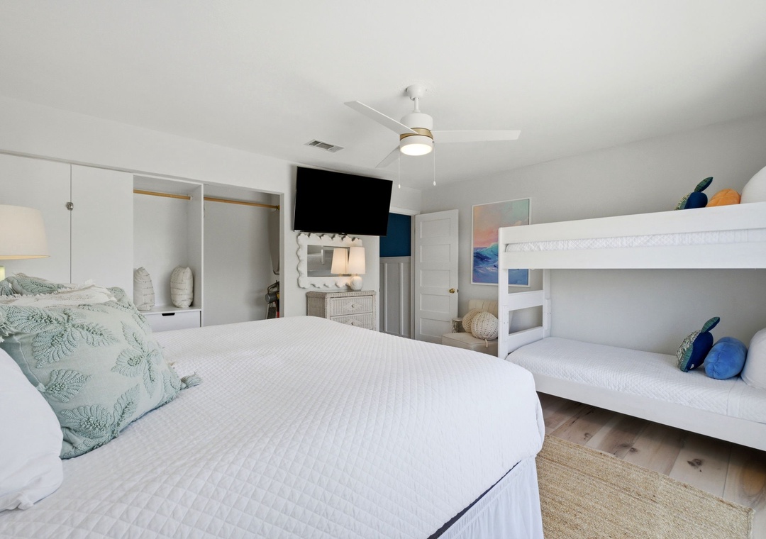 North Lost Key Landing B2- Your bright coastal bedroom features a plush king bed and white bunk beds, perfect for families. Ceiling fan and mounted TV keep everyone comfortable and entertained.