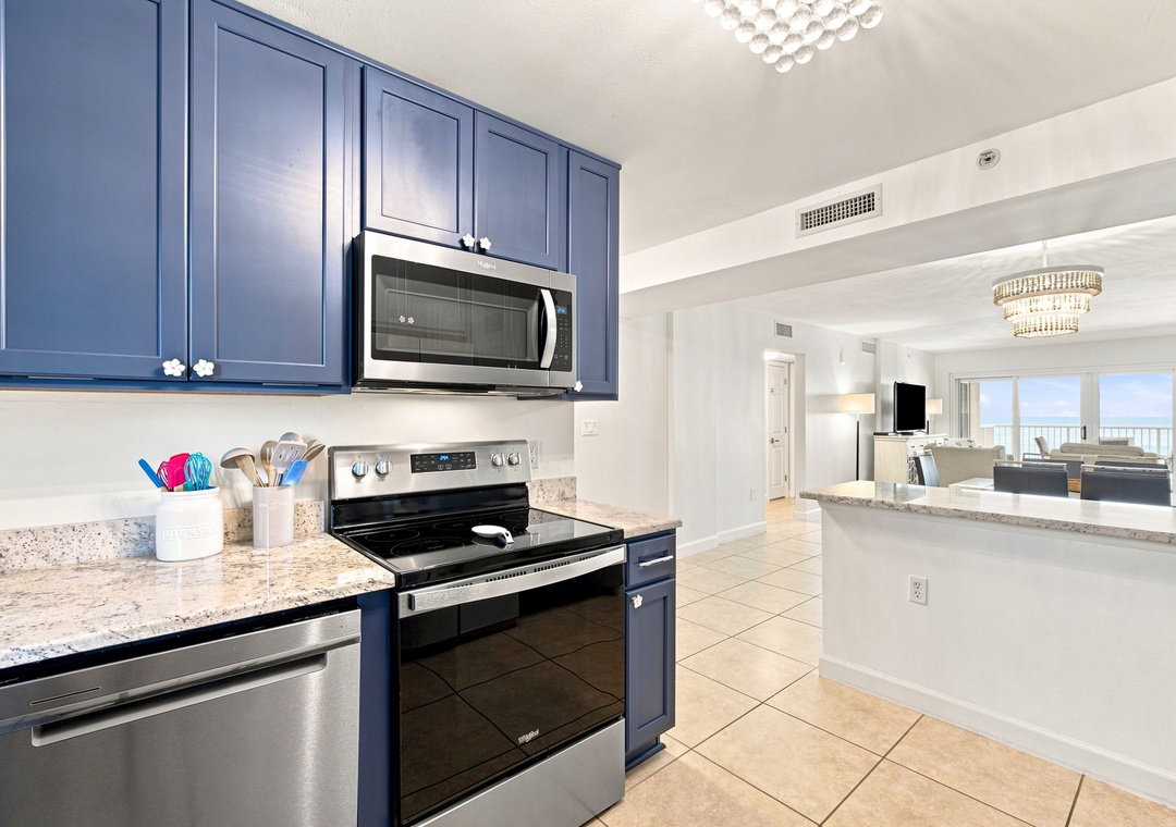 Sandy Key 411- Your fully-equipped kitchen features sleek navy cabinetry, granite counters, and stainless appliances—perfect for preparing meals while soaking in that stunning ocean view just beyond the living area.