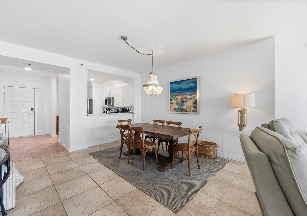 Beach Colony T14B- Gather around the dining table beneath elegant lighting, with your kitchen just steps away and coastal artwork setting a relaxed, beachy mood.