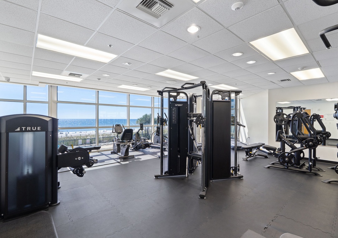Stay on top of your fitness goals in a bright, modern gym with ocean views stretching across the horizon through floor-to-ceiling windows.
