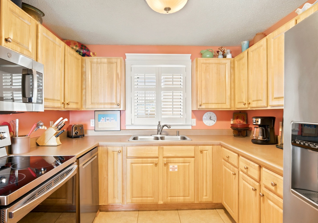 Sandy Key 338- Your fully equipped kitchen awaits with warm wood cabinetry, modern appliances, and cheerful coral walls—perfect for preparing home-cooked meals and morning coffee during your stay.