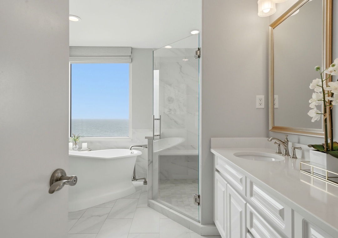 Beach Colony Tower PH1B - Unwind in this serene bathroom where marble elegance meets coastal calm. Soak in the tub with ocean views stretching to the horizon, or refresh in the spacious walk-in shower after a day by the sea.