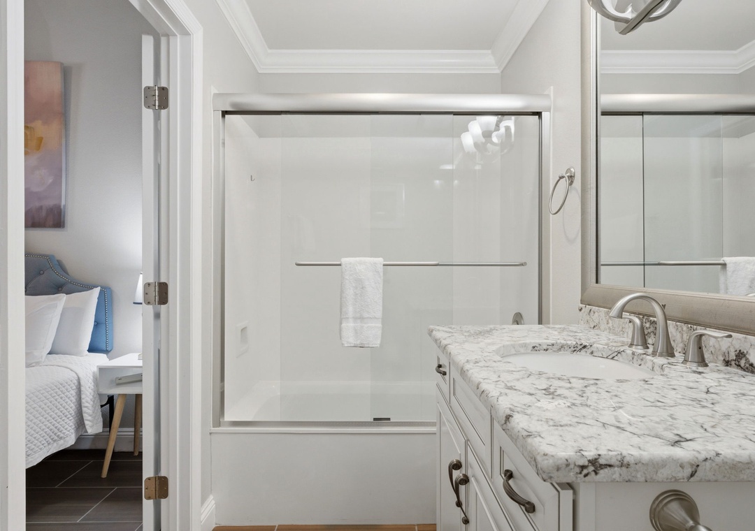 Your private bathroom features a sleek glass shower, elegant granite countertops, and plush towels—everything you need to refresh and unwind after exploring the area.
