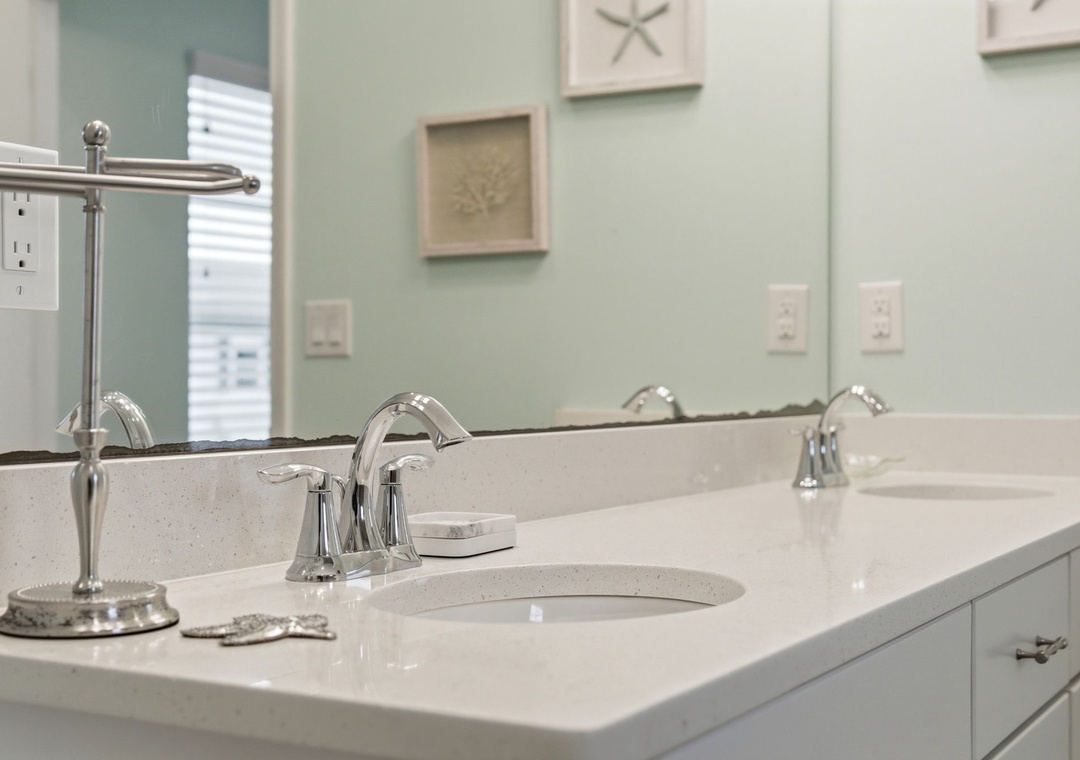 Refresh in your spotlessly clean bathroom featuring gleaming fixtures, coastal-inspired décor, and serene seafoam walls that invite relaxation after a day of adventure.