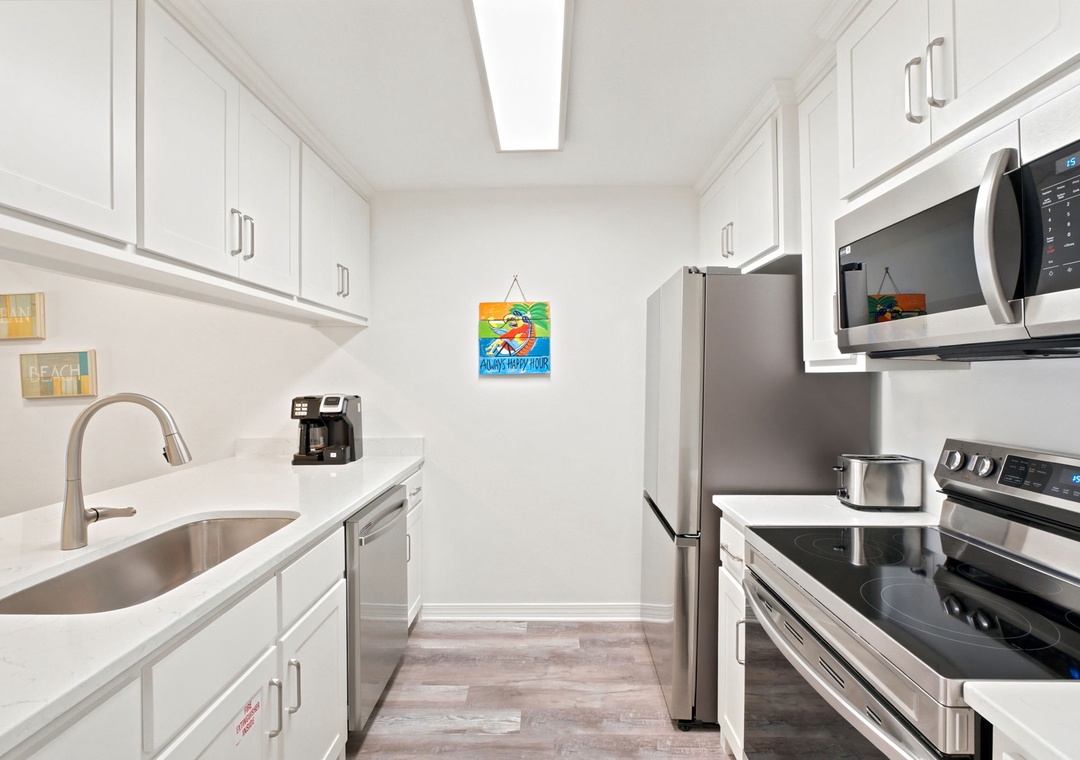 Gulfside Villas 2B- Bright, modern galley kitchen with stainless steel appliances, ample cabinetry, and skylight overhead—perfect for preparing your favorite meals in a clean, airy space.