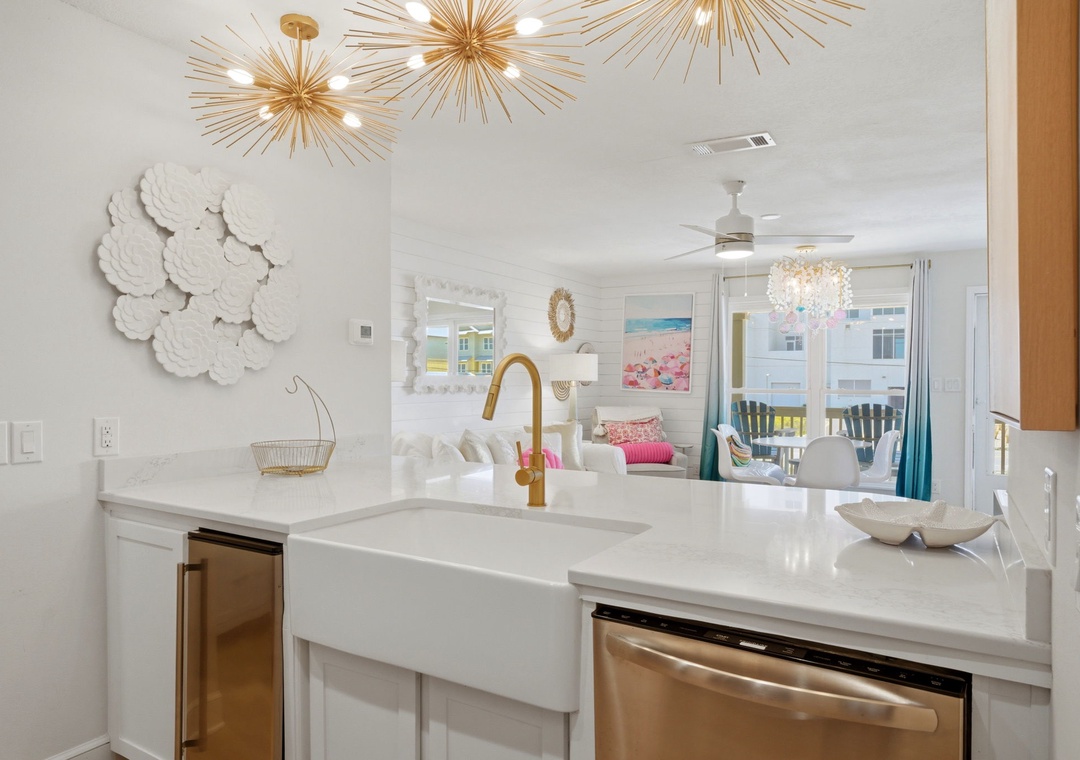 North Lost Key LandinYou'll love preparing meals in this bright, coastal-inspired kitchen with gleaming white countertops, gold fixtures, and stunning starburst lighting overhead. Through the open layout, catch glimpses of the beach and living area beyond