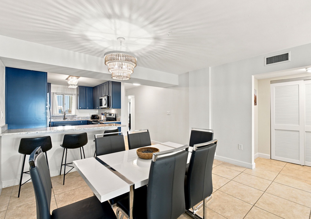 Sandy Key 411- Gather around the elegant dining table with seating for eight, complemented by a stunning crystal chandelier that casts beautiful patterns overhead. The breakfast bar and open kitchen layout invite conversation and togetherness.