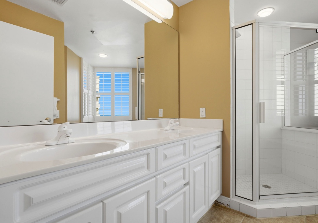 Beach Colony T PH1D- Your spacious bathroom features a walk-in shower, dual vanities, and soft natural light streaming through plantation shutters, creating a bright and refreshing retreat for getting ready each morning.