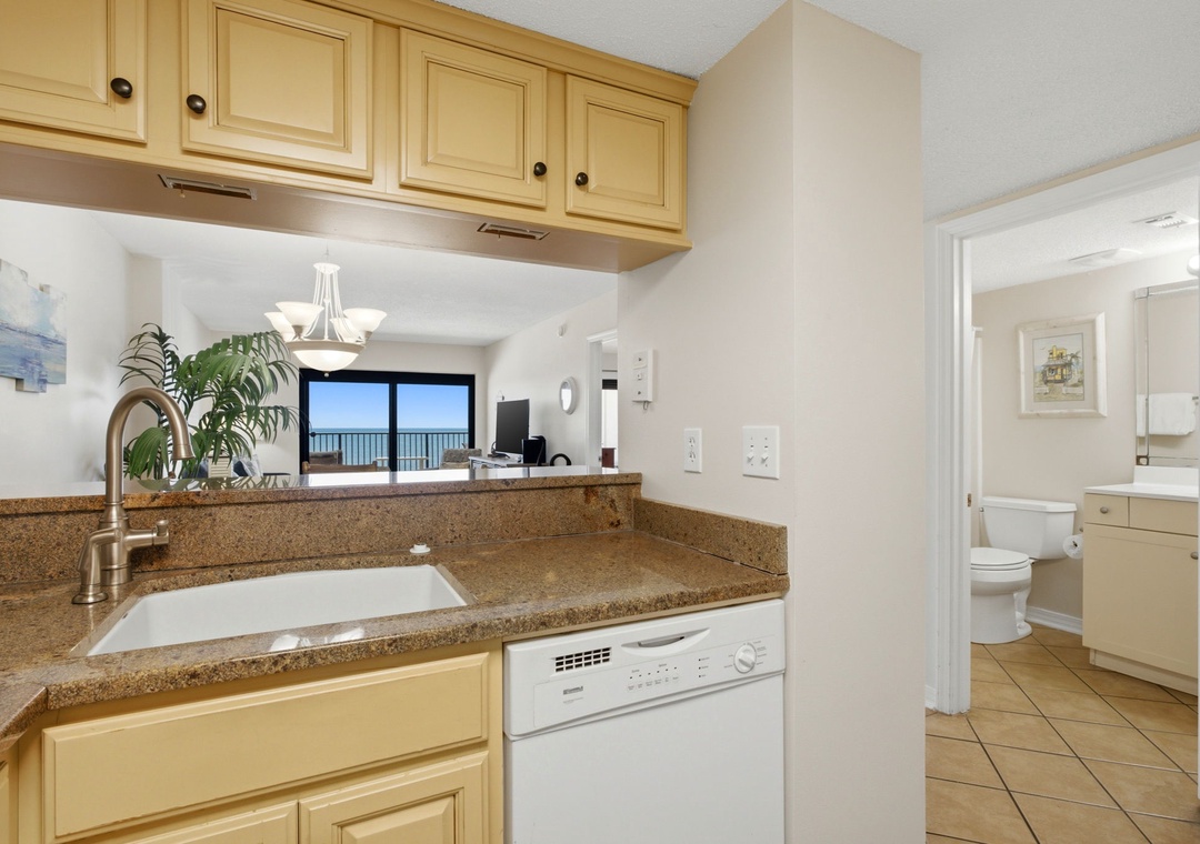 Ocean Breeze E702- Your well-equipped kitchen features granite counters, modern appliances, and opens to a stunning ocean view through the living area—perfect for preparing meals while enjoying the scenery.